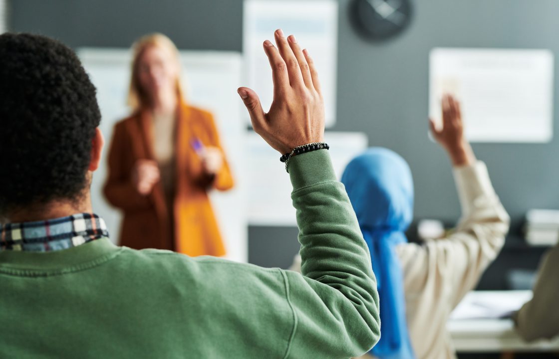 A student raises a hand during a classroom session.