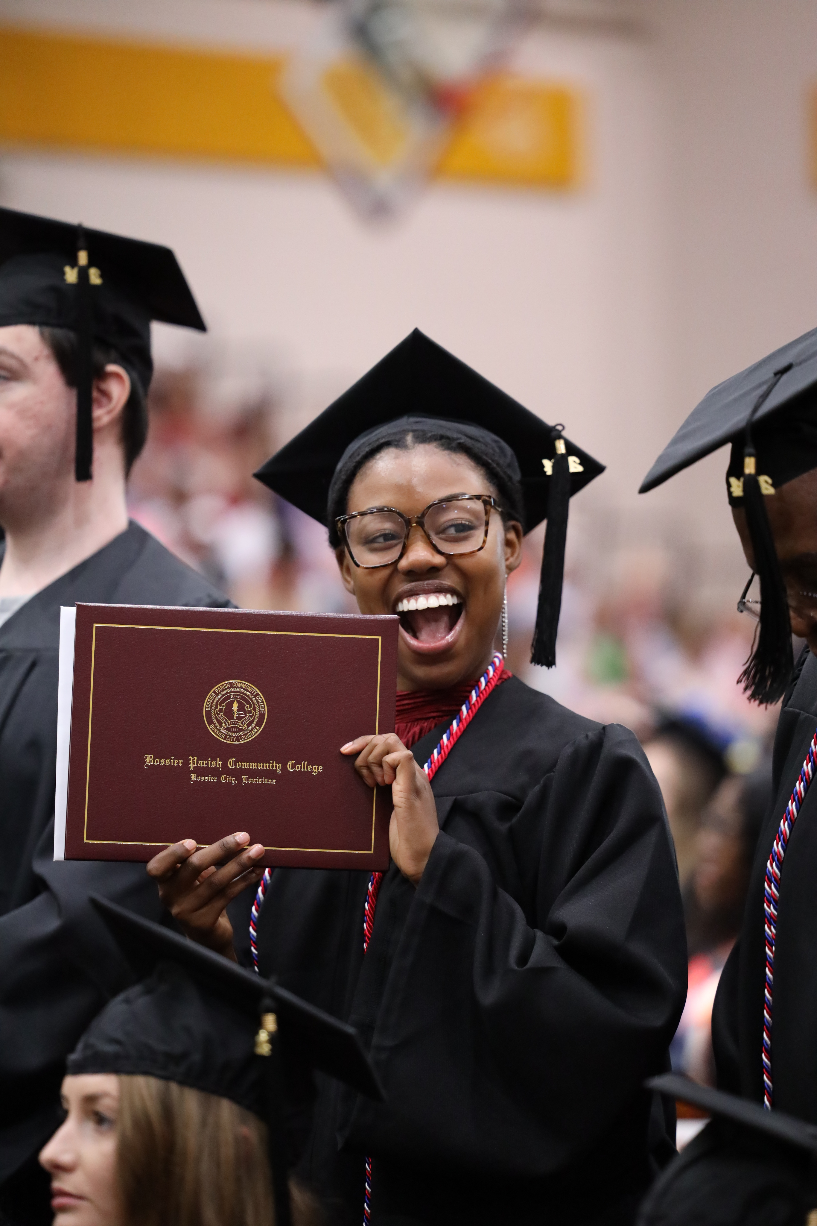 A student with glasses holding books and smiling.